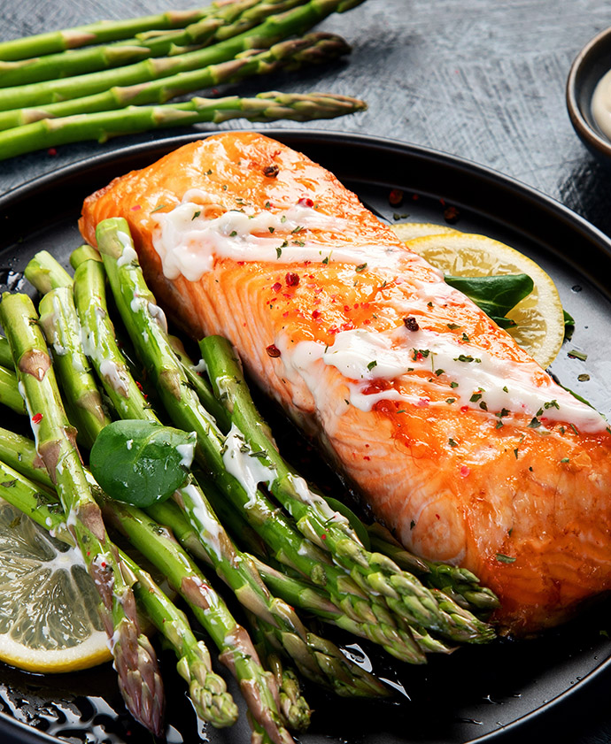 Baked salmon with asparagus on gray background. Mediterranean diet concept.