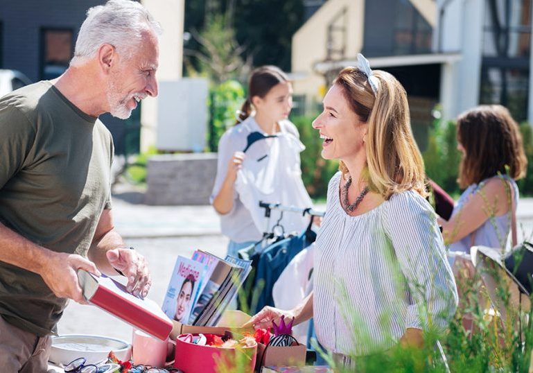 Laughing woman. Appealing good-looking woman laughing while talking to man buying book at yard sale